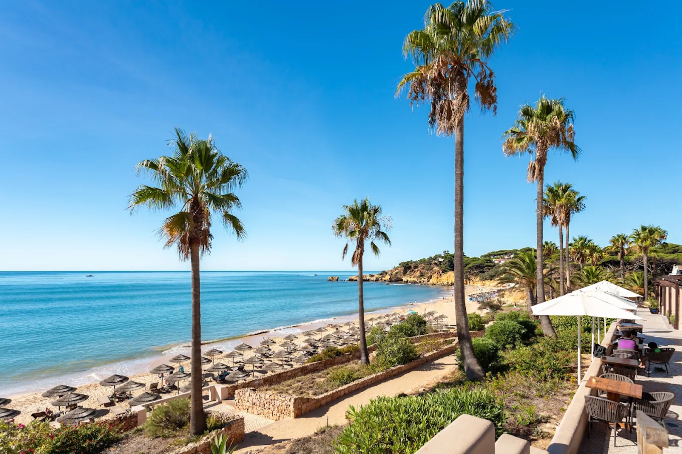 Santa Eulália beach with blue water, palm trees and umbrellas